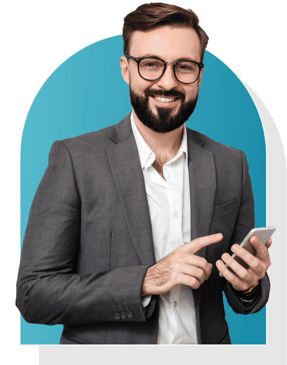 A man with a beard and glasses, wearing a gray suit and white shirt, is smiling while holding a smartphone. He stands in front of a blue arched background.